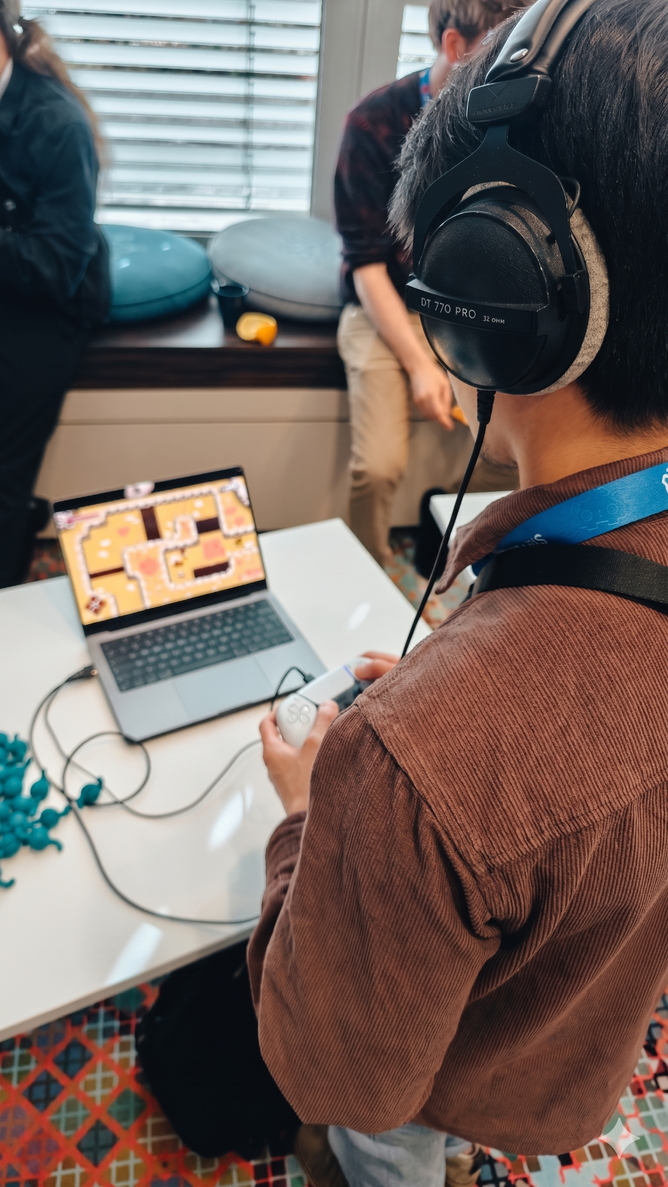 A player at a showcase, wearing big headphones, playing one of our games on a laptop with a small handheld controller.